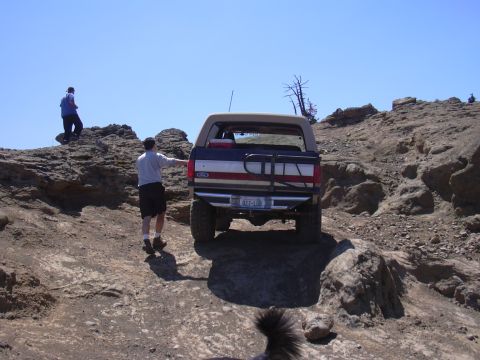 1991 Ford Bronco - A Ford Bronco navigates a rocky trail under a clear blue sky.