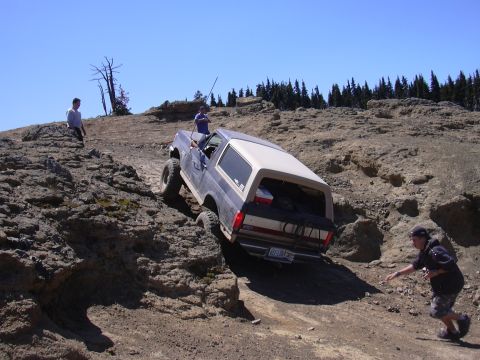 1991 Ford Bronco - A Ford Bronco attempts to climb a steep, rocky terrain with people observing.