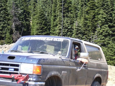 1991 Ford Bronco - Driver in a 1991 Ford Bronco with a club sticker on the windshield, parked in a forest.