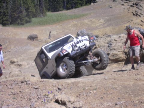 1991 Ford Bronco - A Jeep Wrangler navigates a steep, rocky incline during an off-road excursion.