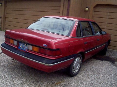 1999 Ford Taurus - This red sedan features a rear view with styling cues from the late 1980s and early 1990s.