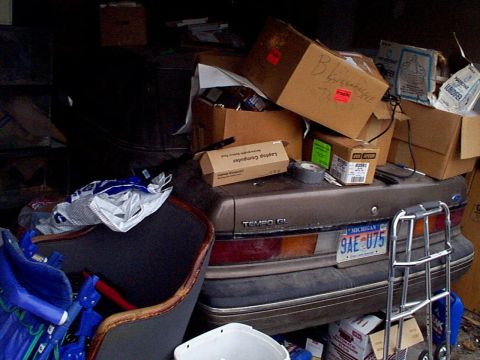 1999 Ford Taurus - A cluttered scene shows the rear of a Ford Tempo GL with boxes piled on its trunk.