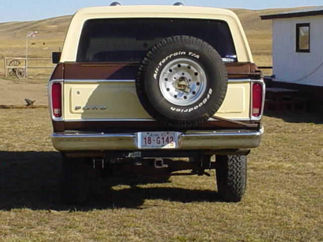 Rear view of a tan and brown 1978 Ford Bronco with a spare tire mounted on the tailgate