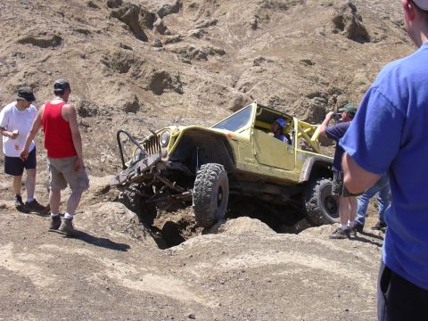1991 Ford Bronco - A modified Jeep tackles a challenging off-road obstacle with spectators observing the action.