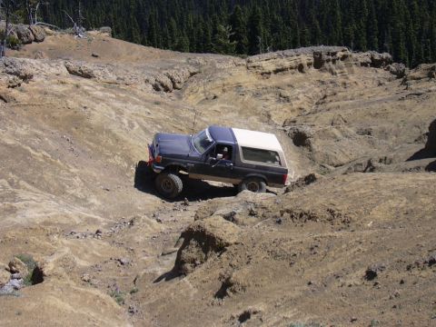 1991 Ford Bronco - Ford Bronco tackling a challenging off-road course in a wooded, mountainous area.