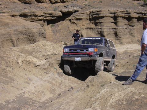 1991 Ford Bronco - This Ford Bronco is navigating a challenging off-road trail with steep inclines and rocky terrain.