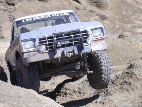 1991 Ford Bronco - Ford Bronco tackling rough off-road trail, equipped with winch and custom grille guard.