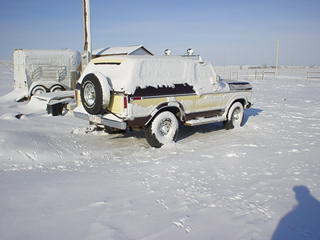 1979 Ford Bronco - A classic Ford Bronco sits covered in snow, with a trailer nearby in a winter landscape.