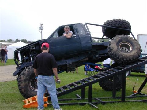 1985 Ford Bronco - A stripped black extended-cab pickup built as a rock buggy, wearing an exo-cage, tube bumper and huge Super Swamper-style bias tires on ste…
