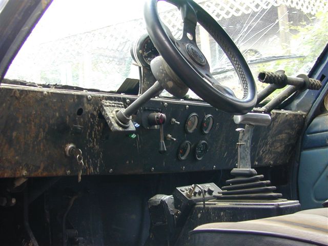 Interior view of a dirty vehicle dashboard with a steering wheel and gear shifter