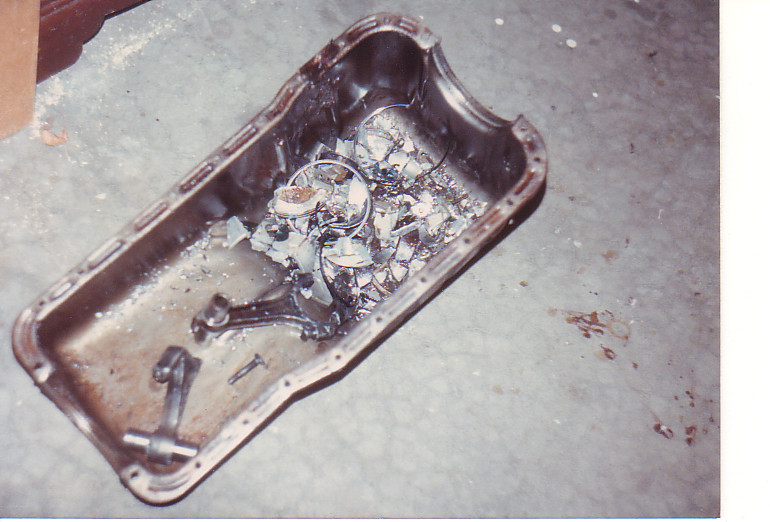 Damaged oil pan filled with shattered metal pieces and connecting rods