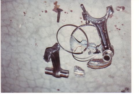 1968 Ford Mustang - Damaged engine components, including a connecting rod and piston rings, lie scattered on a concrete surface.