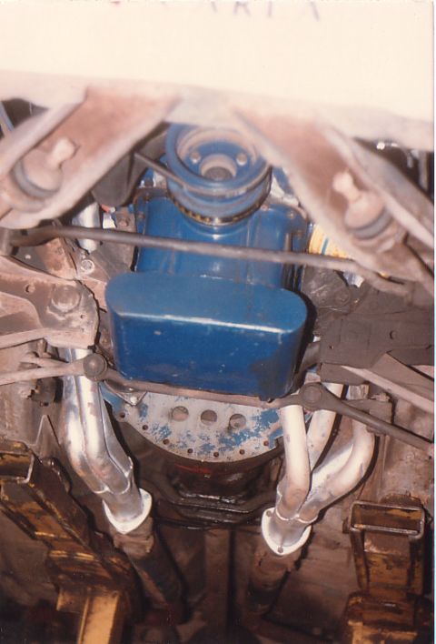 1968 Ford Mustang - Underside view of an engine with blue valve covers and chrome exhaust headers.