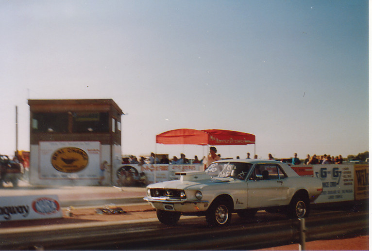 1968 Ford Mustang drag car on track with tower and crowd