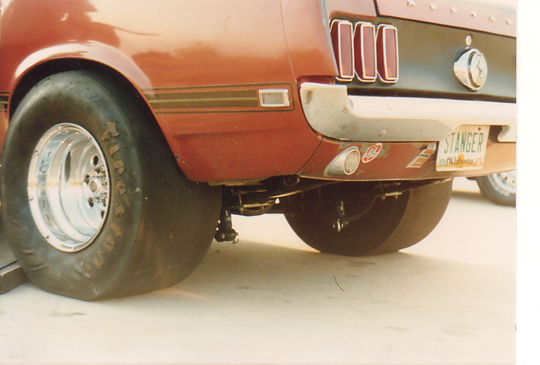 Rear view of a drag car with wide tires and a custom license plate that reads 'STANGER'