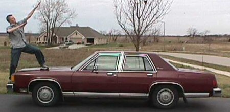 1985 Ford LTD Crown Victoria - Maroon 1985 Ford Crown Victoria LTD sedan parked outside a house with a man posing on its hood.