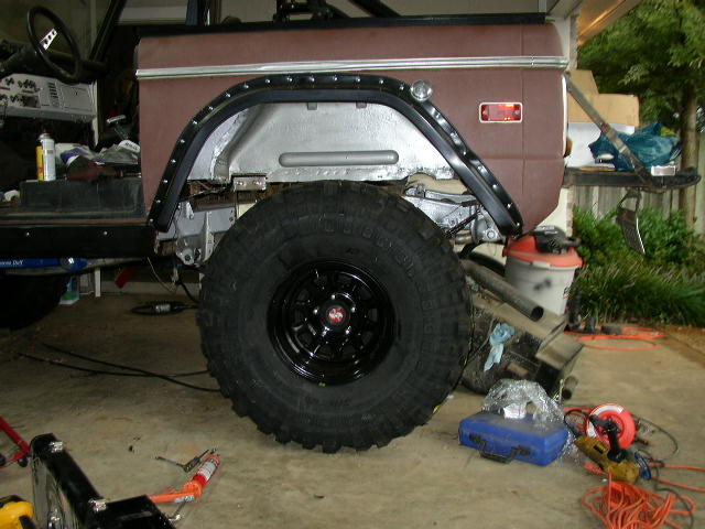 Brown SUV fender and large tire, undergoing restoration