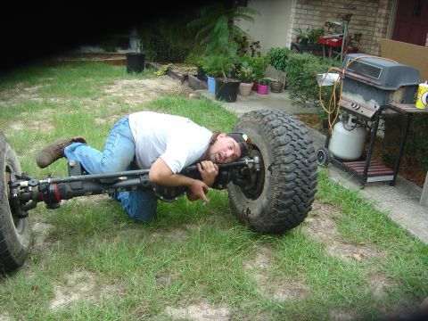 1993 Ford Bronco - A man is shown working on a vehicle's axle and tire assembly, which appears to be a custom modification.