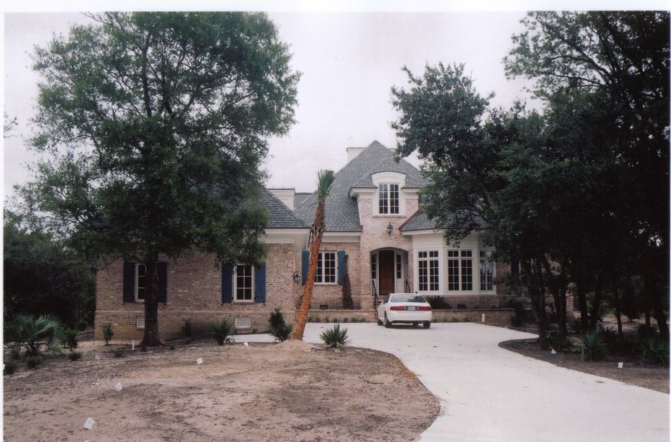 Large two-story brick home with blue shutters and a circular gravel driveway