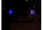 2000 Ford Excursion - The rear of a dark SUV is illuminated by blue lights, making it difficult to discern details.