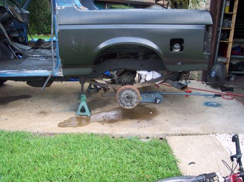1990 Ford Bronco - 1990 Ford Bronco body undergoing work, rear axle removed and vehicle supported by jack stands.