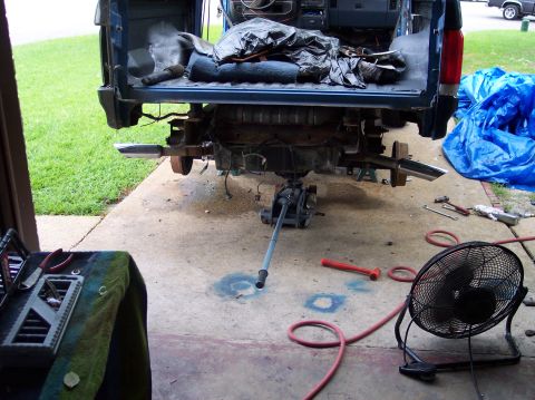 1990 Ford Bronco - The rear axle of a truck is undergoing maintenance, with the vehicle raised and components disassembled.