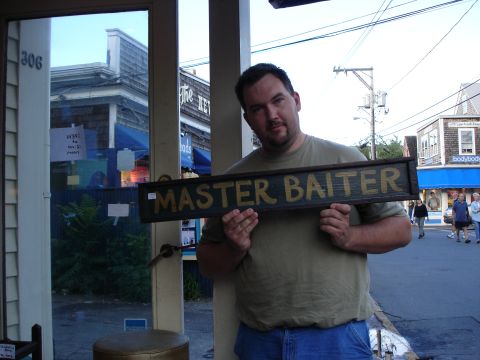 1987 Ford Bronco - Man holds a wooden sign with "MASTER BAITER" painted on it.