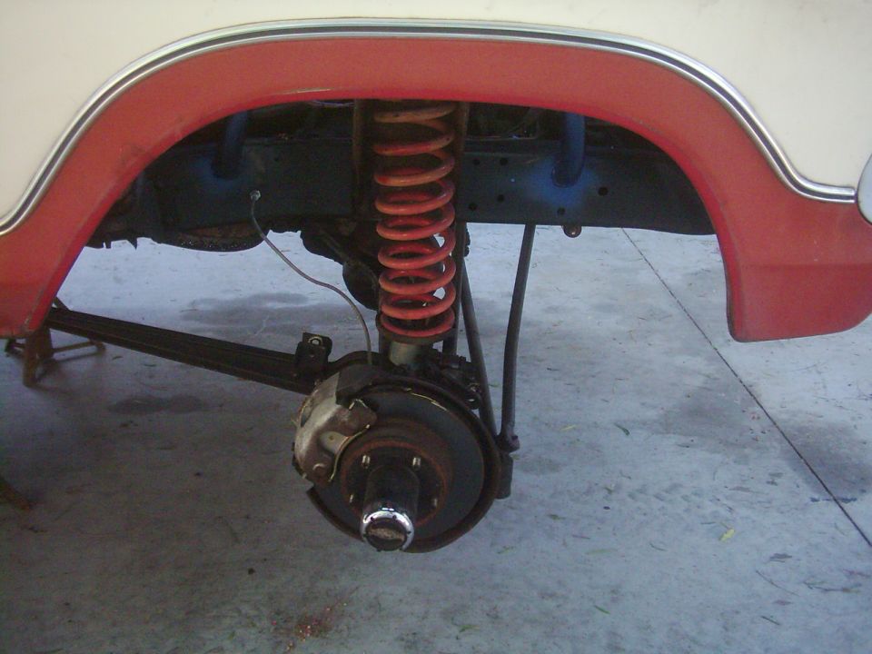 Close-up of a vehicle's front suspension with red coil spring and disc brake assembly