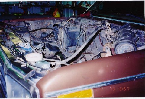 1984 Ford Bronco - The engine bay of a vehicle is shown with various components and wiring exposed, indicating work is in progress.