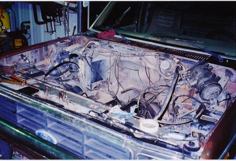 1984 Ford Bronco - The engine bay of a Ford Bronco is shown with the engine removed, revealing the front grille.