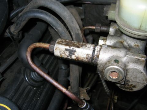 1996 Ford Crown Victoria - Close-up view of a brake master cylinder assembly with visible corrosion and fluid residue.
