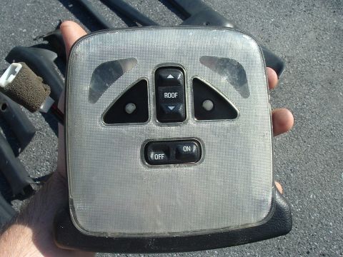 1994 Ford Probe - This overhead console part has buttons for roof control and power, with a textured silver finish.