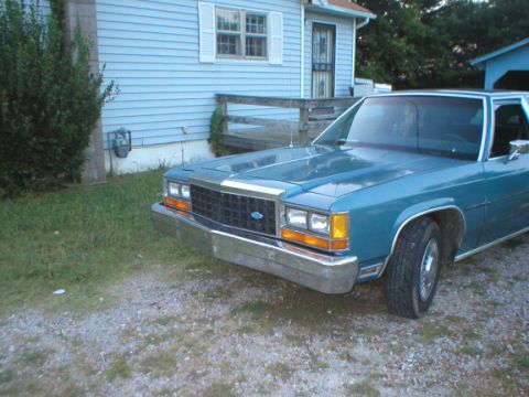 1987 Ford Crown Victoria LTD - A blue 1987 Ford Crown Victoria LTD is parked on a gravel driveway next to a house.