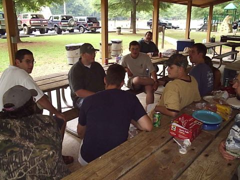 1989 Ford Bronco - Several Ford Broncos are parked at a cookout, with people gathered at picnic tables.