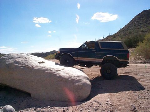 1994 Ford Bronco - This 1994 Ford Bronco navigates a rocky desert terrain under a bright blue sky.