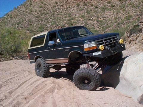 1994 Ford Bronco - This lifted 1994 Ford Bronco navigates a challenging rocky and sandy off-road path.