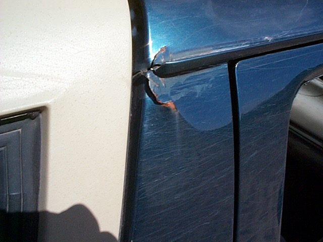 Close-up of cracked paint and rust starting at a body seam on a dark green panel