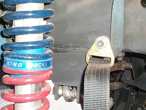 1994 Ford Bronco - Close-up view of a vehicle's suspension system, showing a shock absorber and strap.