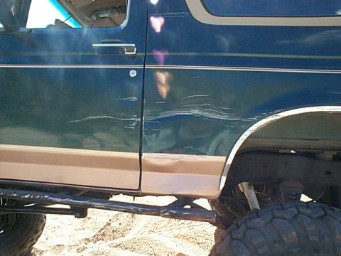 1994 Ford Bronco - This 1994 Ford Bronco displays considerable body damage on its driver's side, impacting both the door and the rear quarter panel.