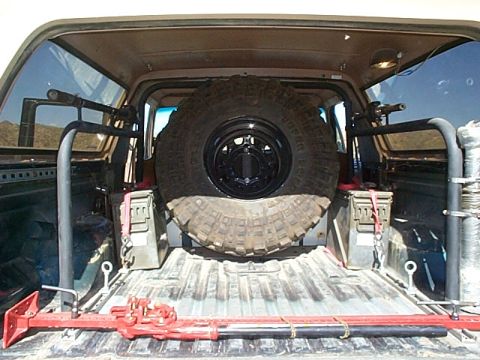 1994 Ford Bronco - Spare tire and off-road equipment stored in the bed of a truck.