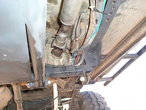 1994 Ford Bronco - The underside of a vehicle reveals its drivetrain, including the transfer case and driveshaft, with visible suspension parts.