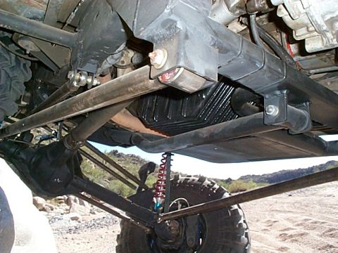 1994 Ford Bronco - The complex undercarriage of a modified off-road vehicle is visible, with heavy-duty suspension and drivetrain parts.