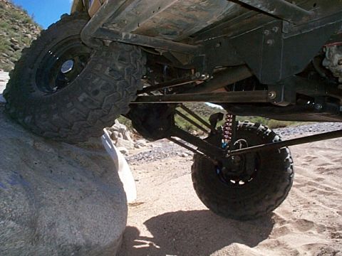 1994 Ford Bronco - The underside of an off-road vehicle shows its suspension and large tires, with one tire on a rock.