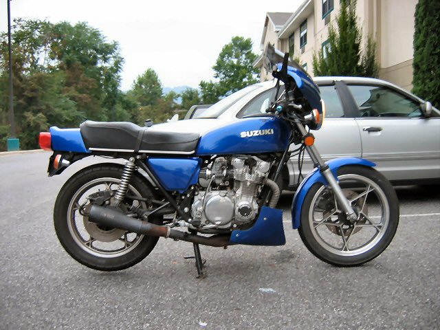 Blue Suzuki motorcycle parked next to a silver car