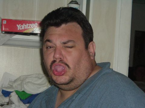 1993 Ford Taurus - A man makes a silly face with his tongue out and one eye winking, with a Yahtzee box visible.