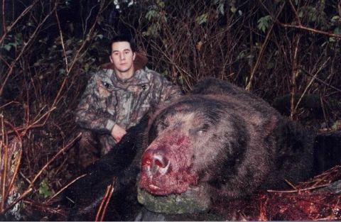 1993 Ford Bronco - A hunter poses with a large bear carcass in a wooded area.