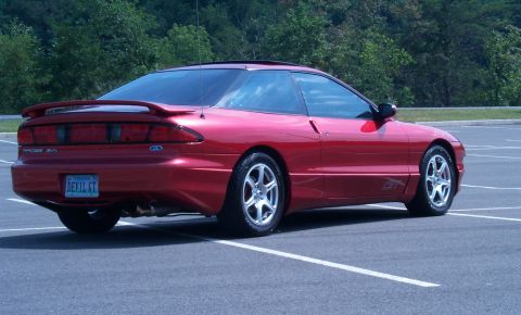 1996 Ford Probe - This red Ford Probe GT is parked in an empty lot with trees in the background.