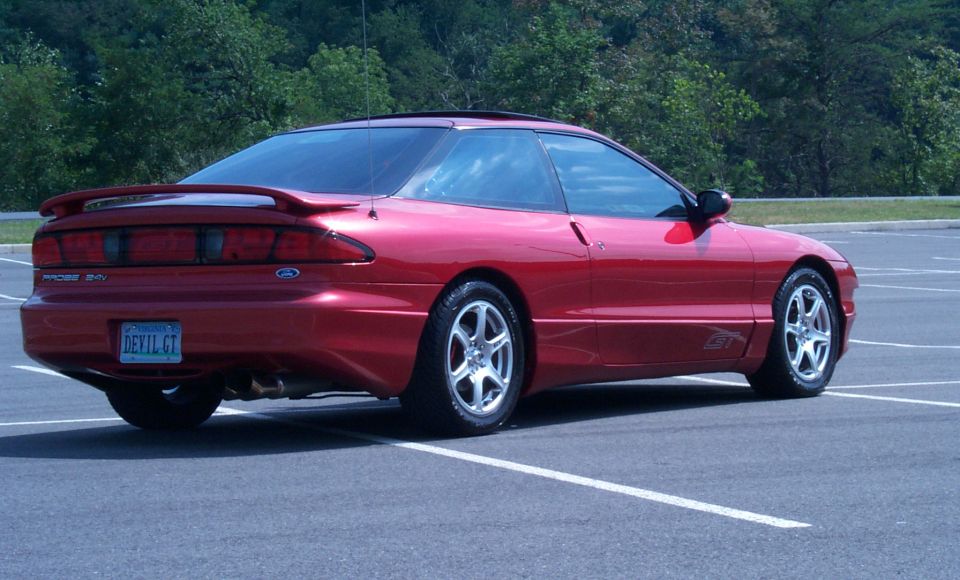 Red Ford Probe GT coupe rear 3/4 view with 'DEVIL GT' plate in parking lot