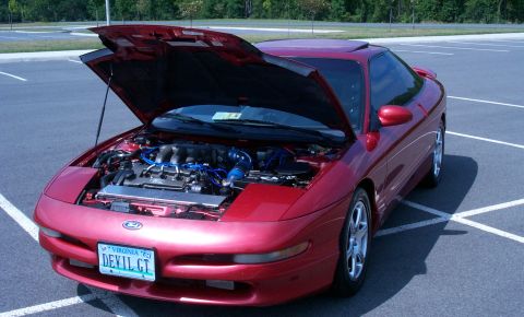 1996 Ford Probe - A red 1996 Ford Probe is parked with its hood open, revealing the engine bay and a custom license plate.