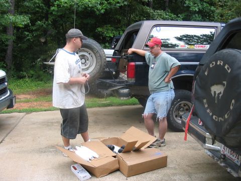 1988 Ford Bronco - Two men are standing next to two Ford Broncos with boxes on the ground.